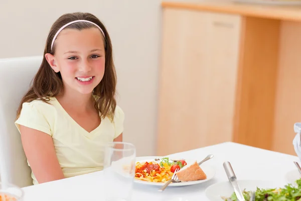 Lachende meisje met diner aan tafel — Stockfoto