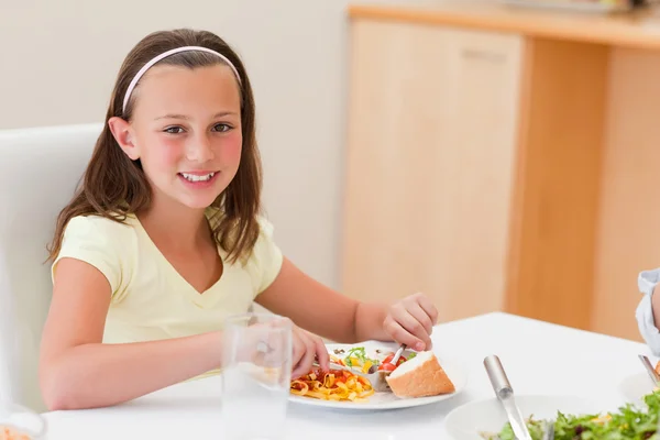 Lächelndes Mädchen beim Abendessen am Tisch — Stockfoto