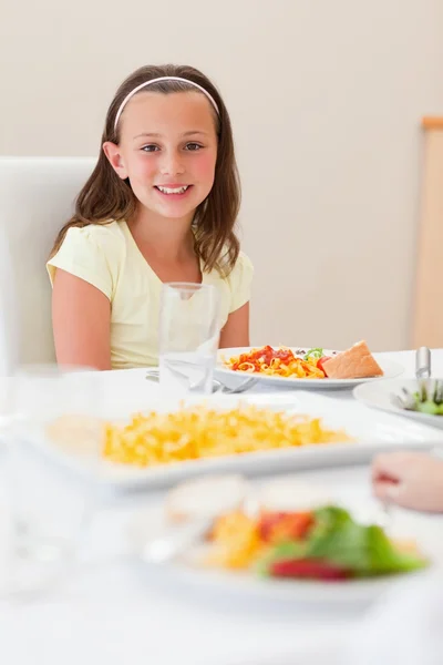 Usmívající se dívka sedí u jídelního stolu — Stock fotografie