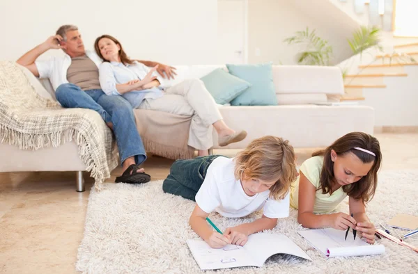 Brother and sister doing homework on the carpet — Stock Photo, Image