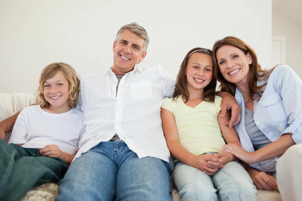 Familia feliz sentada en el sofá — Foto de Stock