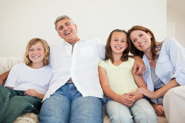 Riendo familia sentada en el sofá — Foto de Stock