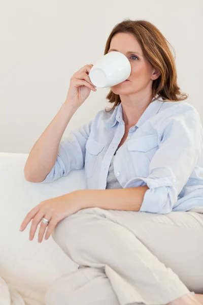 Kobieta pijąca kawę na kanapie — Zdjęcie stockowe