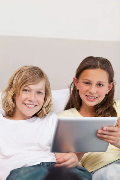 Irmão e irmã usando tablet no sofá — Fotografia de Stock