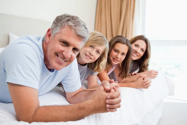 Glad familj ligger på sängen — Stockfoto