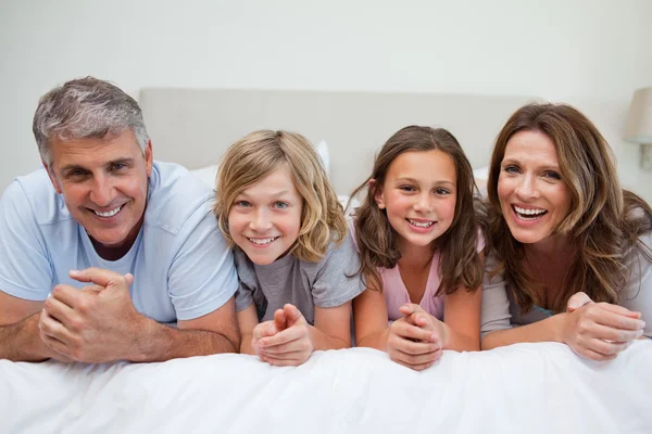 Sorrindo família deitada na cama — Fotografia de Stock