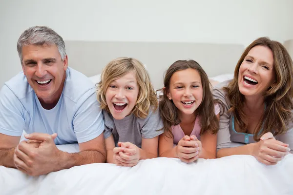 Смеющаяся семья лежит на кровати — стоковое фото