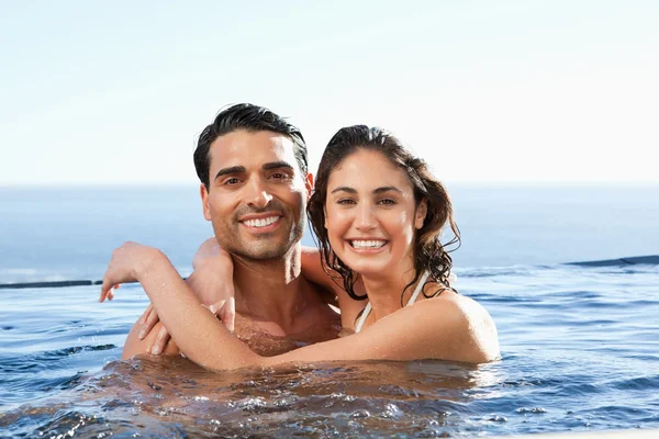 Smiling couple embracing in the pool — Stock Photo, Image