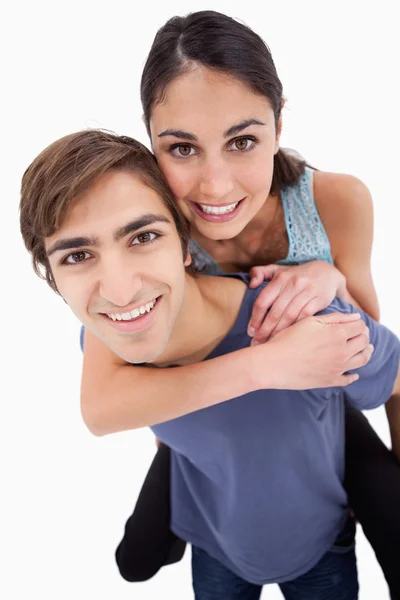 Portrait of a young man holding his girlfriend on his back — Stock Photo, Image