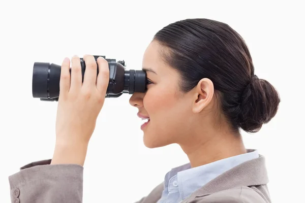 Sidovy av en affärskvinna som tittar genom kikare — Stockfoto