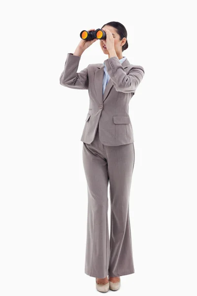 Portrait of a brunette businesswoman looking through binoculars — Stock Photo, Image