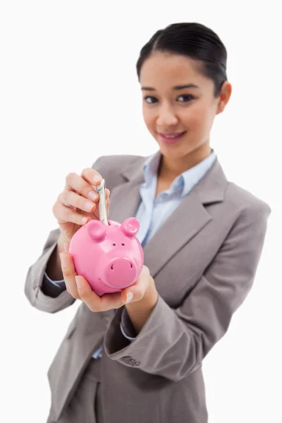 Retrato de uma mulher de negócios colocando uma nota bancária em um banco porquinho — Fotografia de Stock