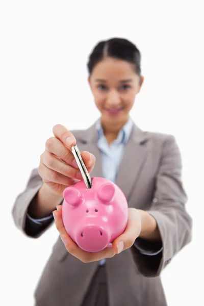 Retrato de uma jovem empresária colocando uma nota bancária em um porquinho — Fotografia de Stock