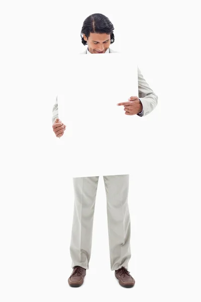 Homme d'affaires regardant et pointant vers signe blanc dans ses mains — Photo