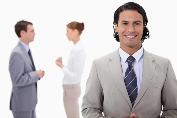 Businessman with talking colleagues behind him — Stock Photo, Image