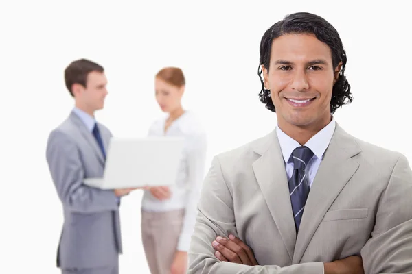 Uśmiechający się biznesmen z kolegami w pracy na laptopie za nim — Zdjęcie stockowe