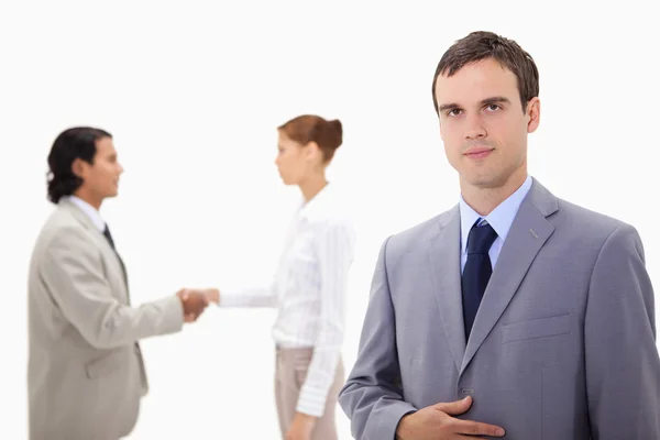 Businessman with hand shaking colleagues behind him — Stock Photo, Image