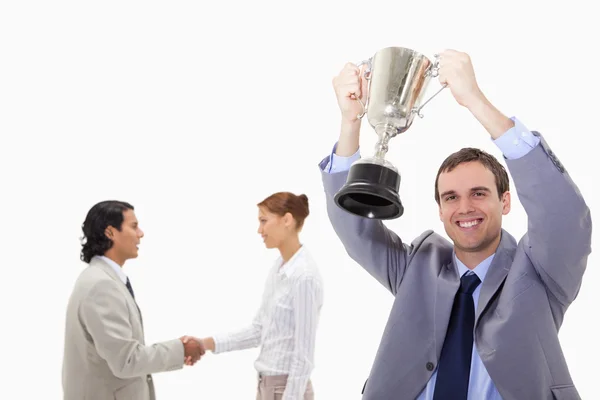 Businessman raising cup with hand shaking colleagues behind him — Stock Photo, Image