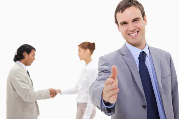 Businessman extending hand with hand shaking colleagues behind h — Stock Photo, Image