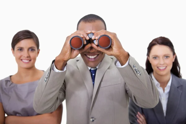 Empresário sorridente com colegas olhando através de binóculos — Fotografia de Stock