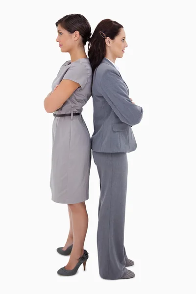 Businesswomen with arms folded standing back on back — Stock Photo, Image