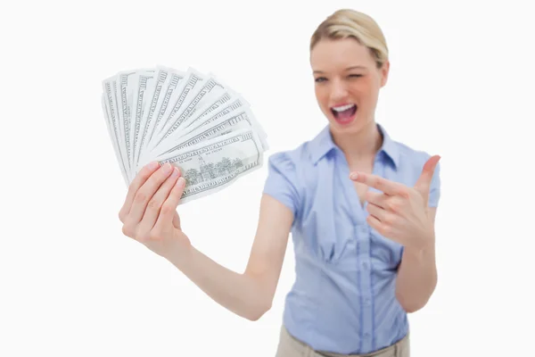 Woman holding money and pointing at it — Stock Photo, Image