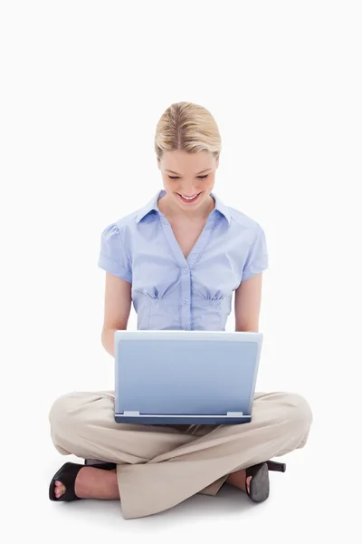 Улыбающаяся сидящая женщина работает над своим ноутбуком — стоковое фото