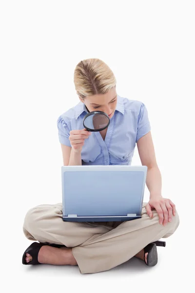 Mulher usando lupa para olhar para seu laptop — Fotografia de Stock