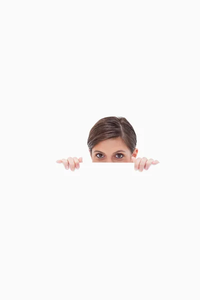 Sneaky woman looking over blank wall — Stock Photo, Image