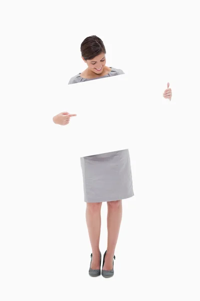 Woman pointing at blank sign in her hands — ストック写真