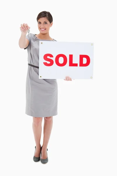 Donna con cartello venduto consegna chiave — Foto Stock