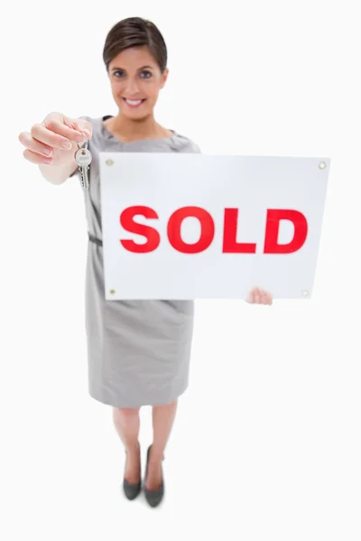 Agente inmobiliario con letrero vendido que entrega la llave — Foto de Stock