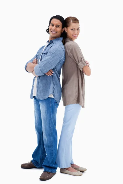Sonriente joven pareja de pie espalda con espalda — Foto de Stock
