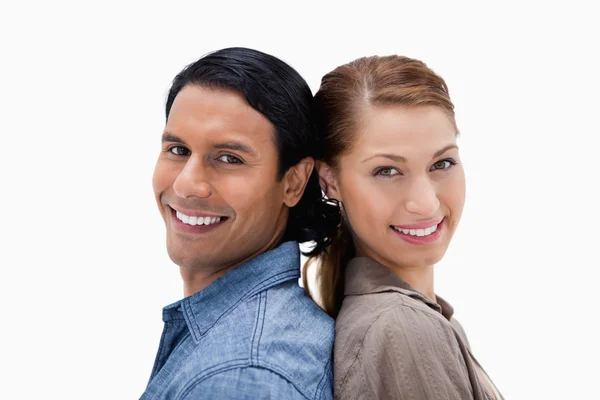 Side view of smiling couple standing back to back — Stock Photo, Image