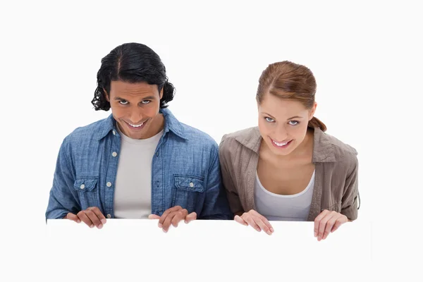 Smiling couple looking over blank wall — Stock Photo, Image