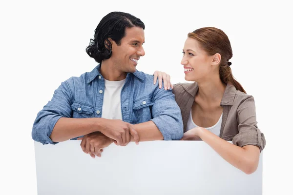 Smiling couple leaning on blank wall — Stock Photo, Image