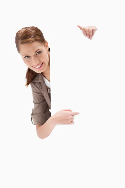 Smiling woman pointing around blank sign — Stock Photo, Image