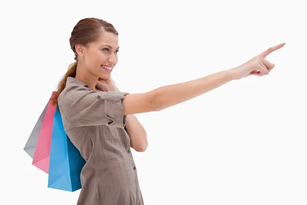 Vista lateral de la mujer que apunta con bolsas de compras —  Fotos de Stock