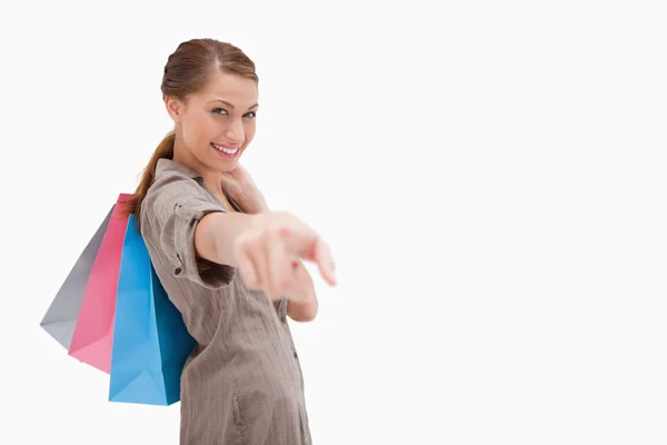Widok z boku uśmiechnięta kobieta wskazując z torby na zakupy — Zdjęcie stockowe