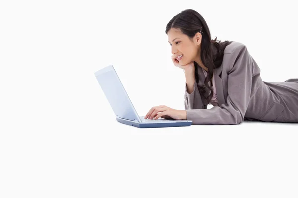 Widok z boku leżącej kobiety za pomocą laptopa — Zdjęcie stockowe