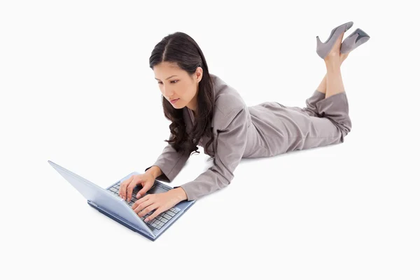 Mulher deitada trabalhando em seu laptop — Fotografia de Stock