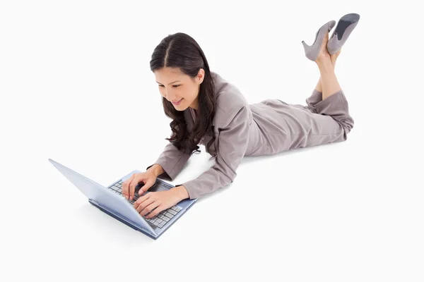Liegen vrouw die werkt op haar laptop — Stockfoto