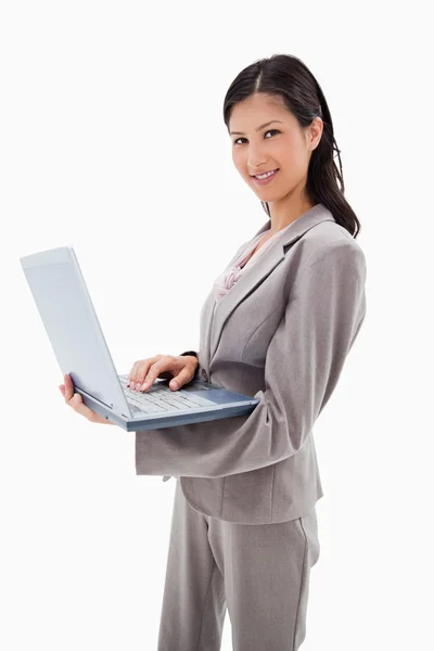 Vista laterale della donna d'affari sorridente in piedi con il computer portatile — Foto Stock