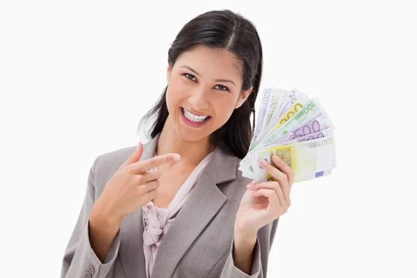 Femme d'affaires souriante pointant son argent — Photo