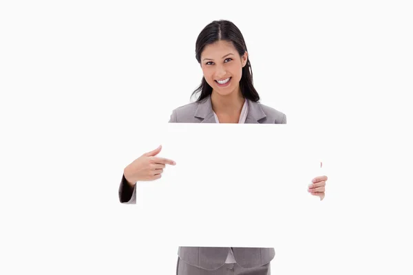 Empresária sorridente apontando para placa de sinal em branco — Fotografia de Stock