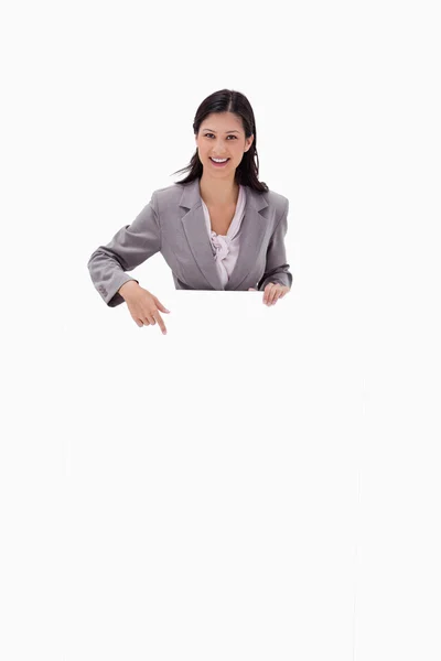 Lächelnde Geschäftsfrau zeigt auf leeres Schild — Stockfoto