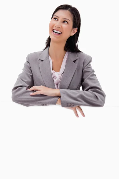 Smiling businesswoman leaning on a blank wall — Stock Photo, Image