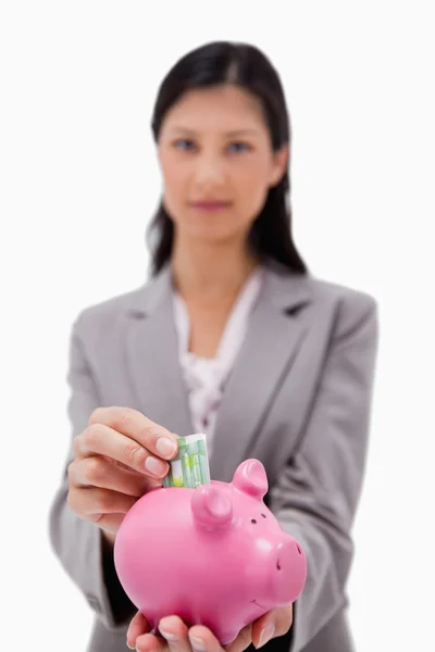 Geld wordt gestoken piggy bank door zakenvrouw — Stockfoto