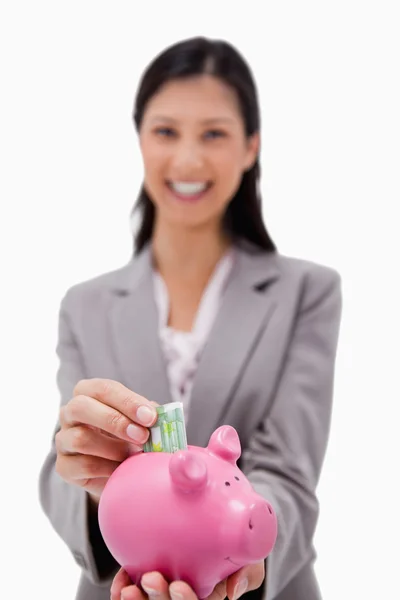 Pengar sätts i spargris av leende affärskvinna — Stockfoto