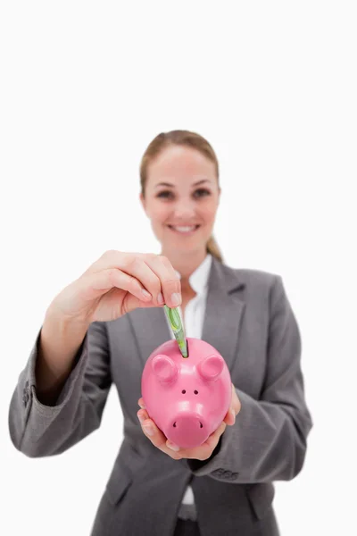 Dinheiro sendo colocado no banco porquinho por sorrindo empregado do banco — Fotografia de Stock